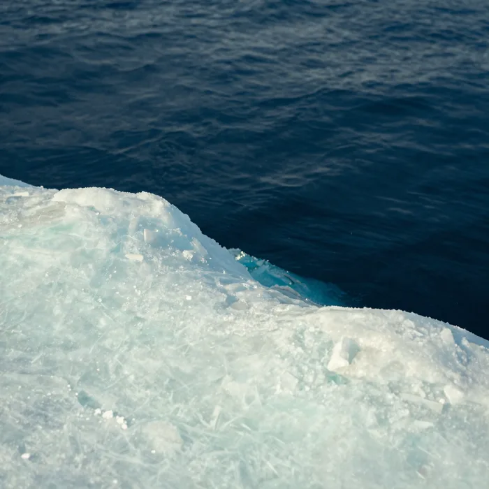The edge of Arctic sea ice meeting dark cold water, pale mint and navy