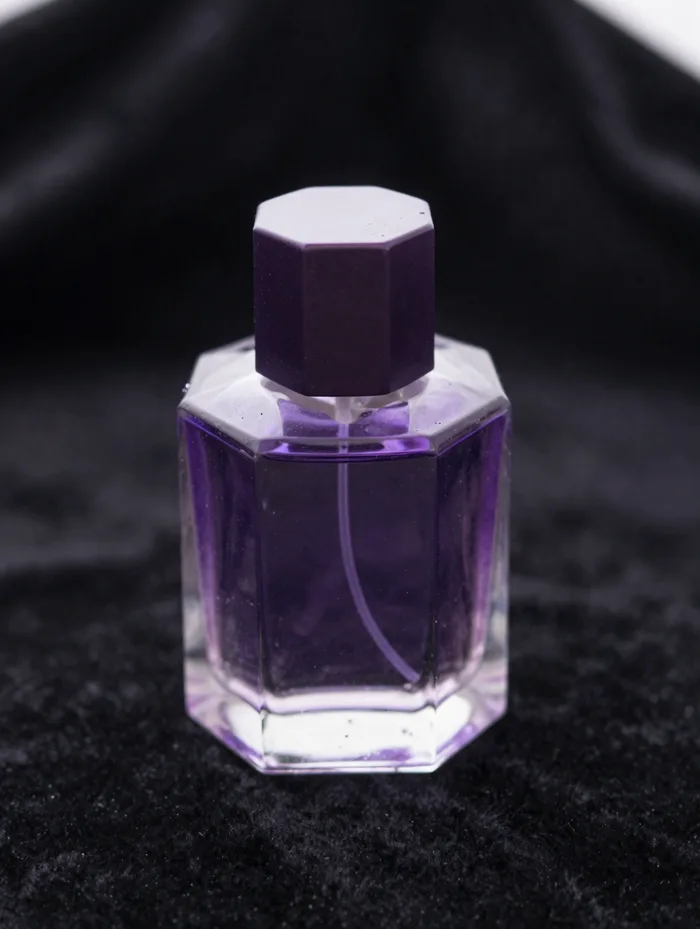 A faceted perfume bottle glowing amethyst on black velvet, luxurious