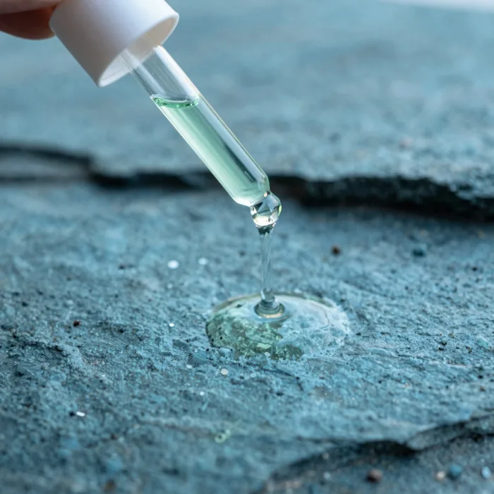 A dropper of mineral serum over a tide pool, cool teal and slate
