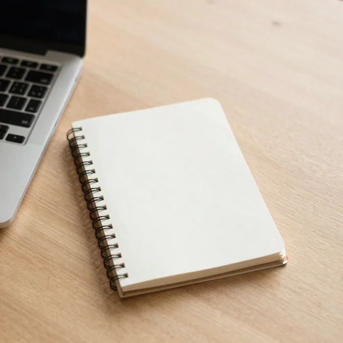 A clean flat-lay of a laptop and notebook on a warm desk
