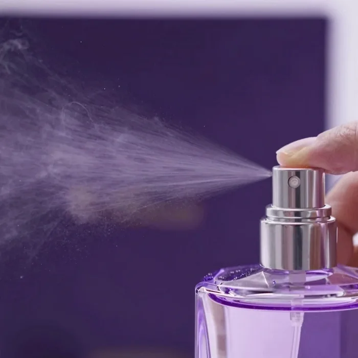 A close-up of perfume being sprayed, a fine violet mist
