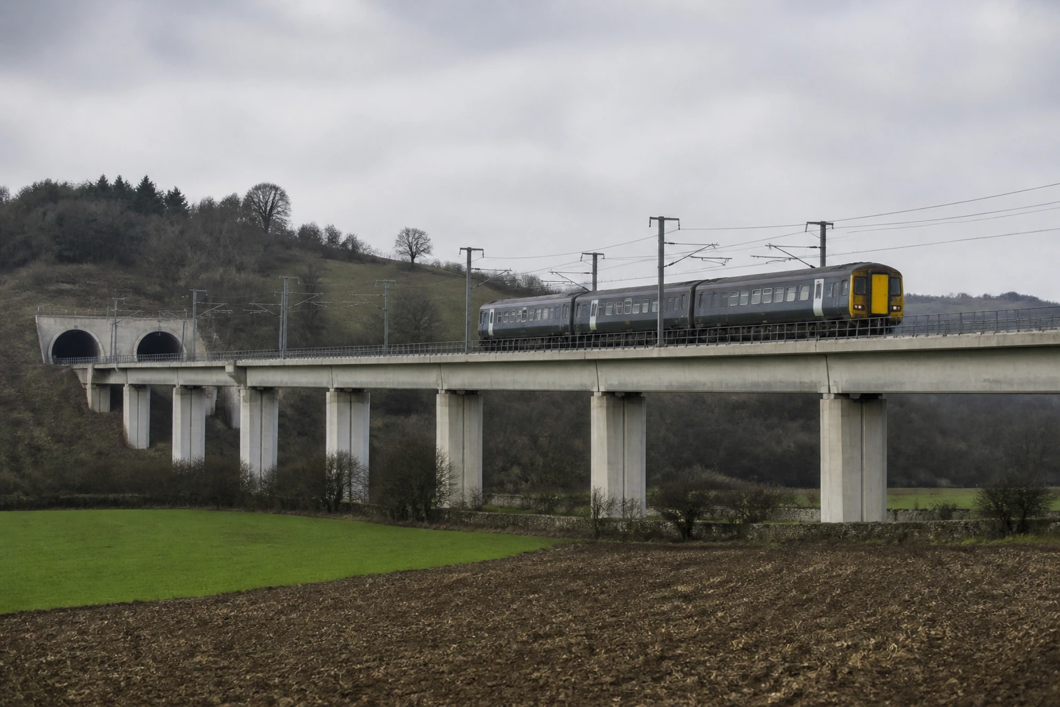 A concrete rail viaduct crossing a shallow valley, seen from below