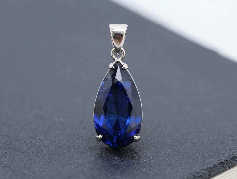 A tourmaline drop pendant on platinum against deep midnight blue, sparkling facets