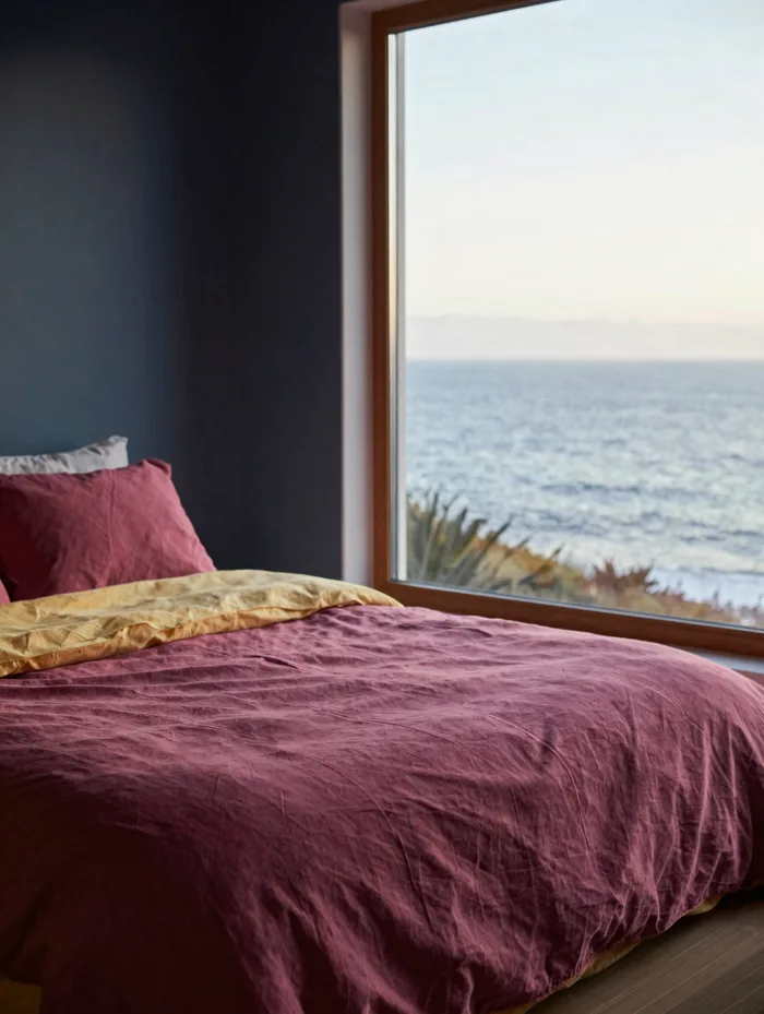 A serene ocean-view retreat cabin interior with linen bedding, soft morning light